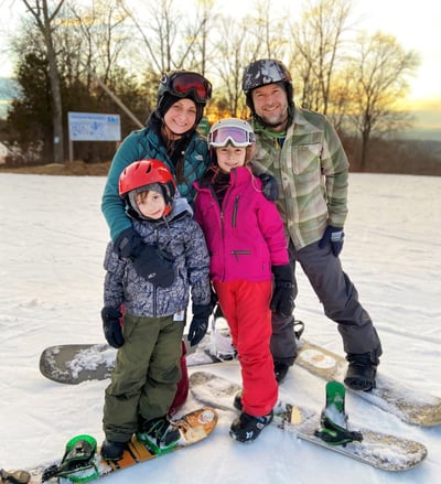 Family of four snowboarding at the top of the mountain