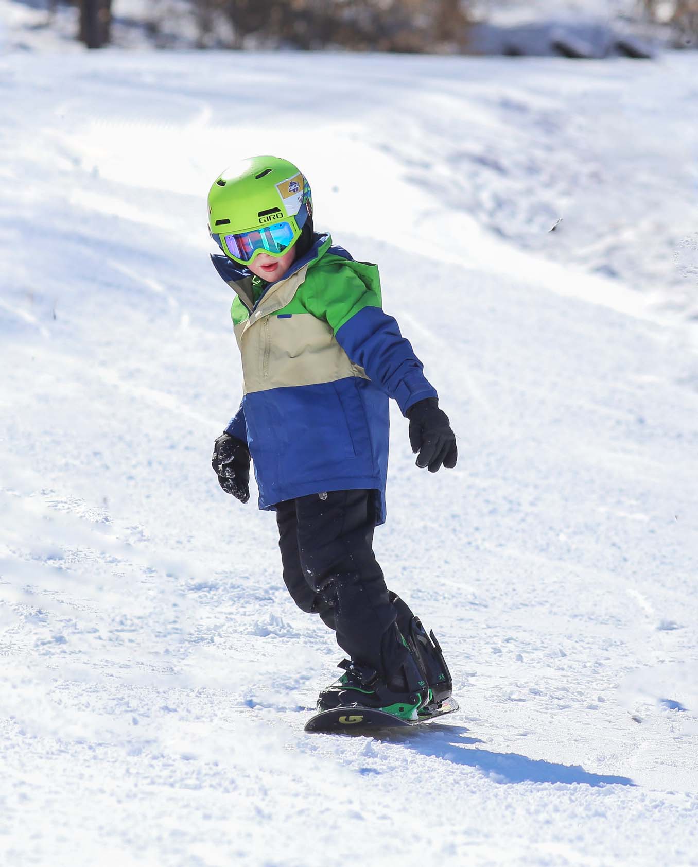 Child snowboarding down mountain.